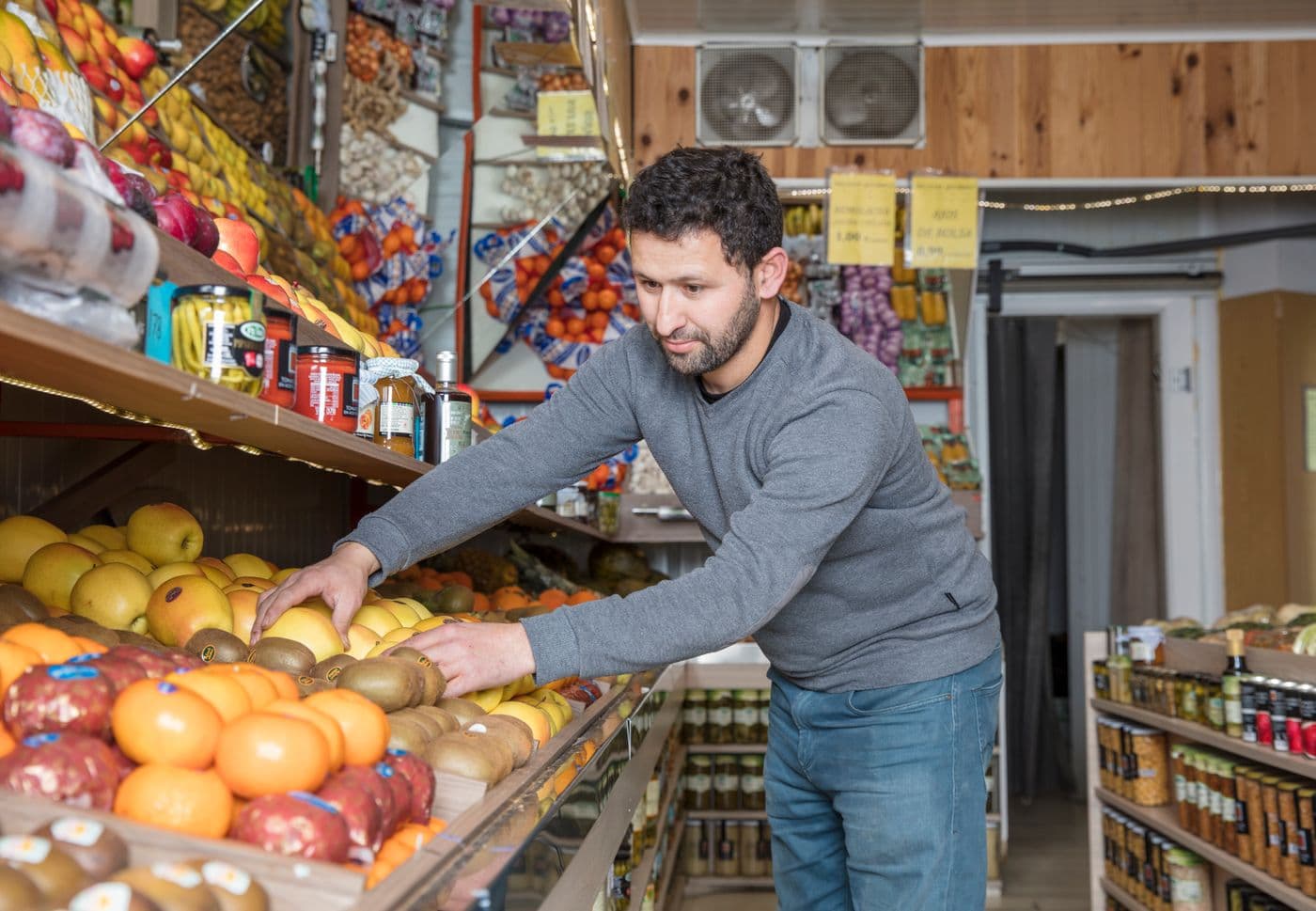 A shopkeeper arranging fresh fruit in a neighborhood grocery